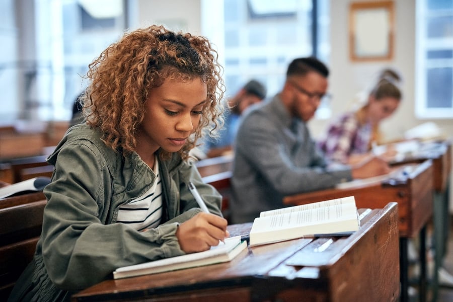 Student writing in a classroom