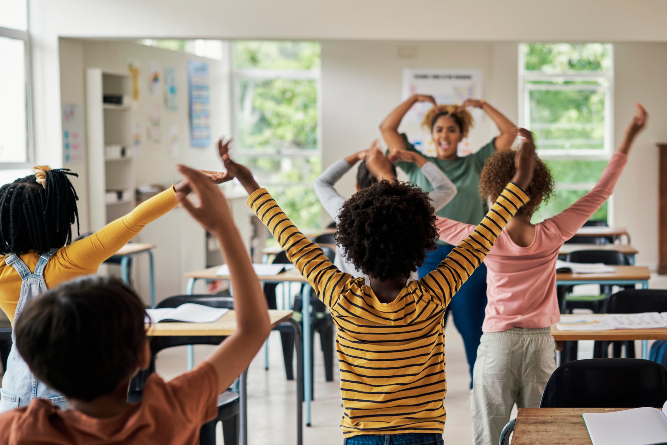 School, classroom and children learning a dance with their teacher excited, happy and fun. Diversity, education and kids with woman teaching, dancing and enjoying educational creative lesson together